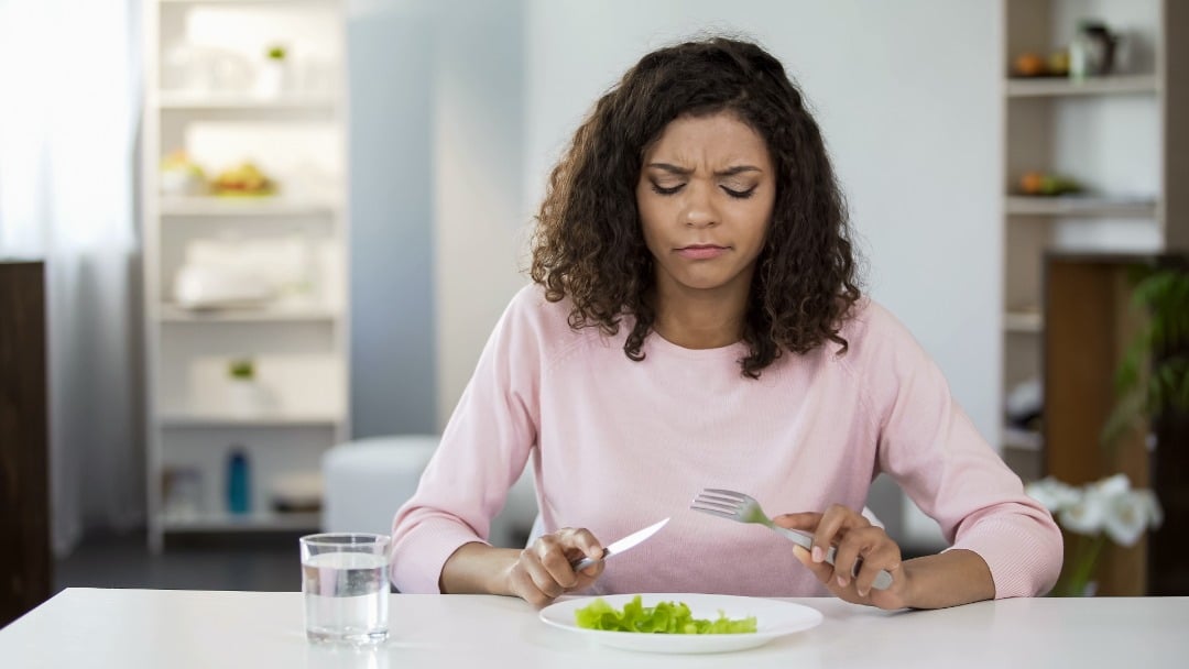 Woman looking at her plate of food in disgust.